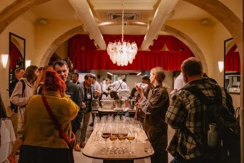 A nighttime crowd holding wine glasses outside a Lisbon bistro with a red awning.