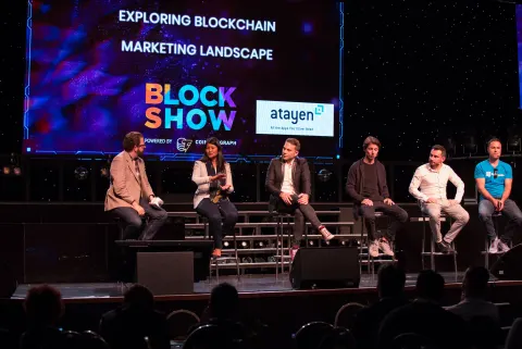 A panel of six speakers seated on stage at BlockShow Europe 2018 in front of a large conference screen.