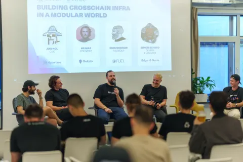 A panel of five speakers on stage in front of a screen reading 'Building Crosschain Infra in a Modular World'.