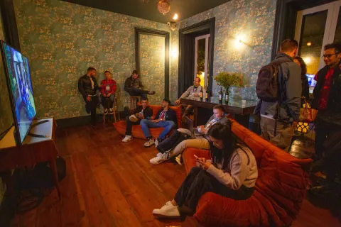 Two men in a fireside chat on blue armchairs at Crypto Party, one holding a Cointelegraph microphone, sponsor logos on the screen behind.