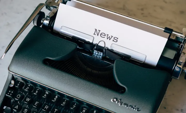 A vintage Olympia typewriter with a sheet of paper that reads 'News'.