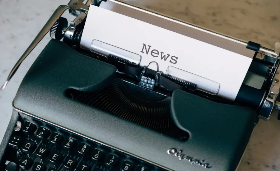 A vintage Olympia typewriter with a sheet of paper that reads 'News'.